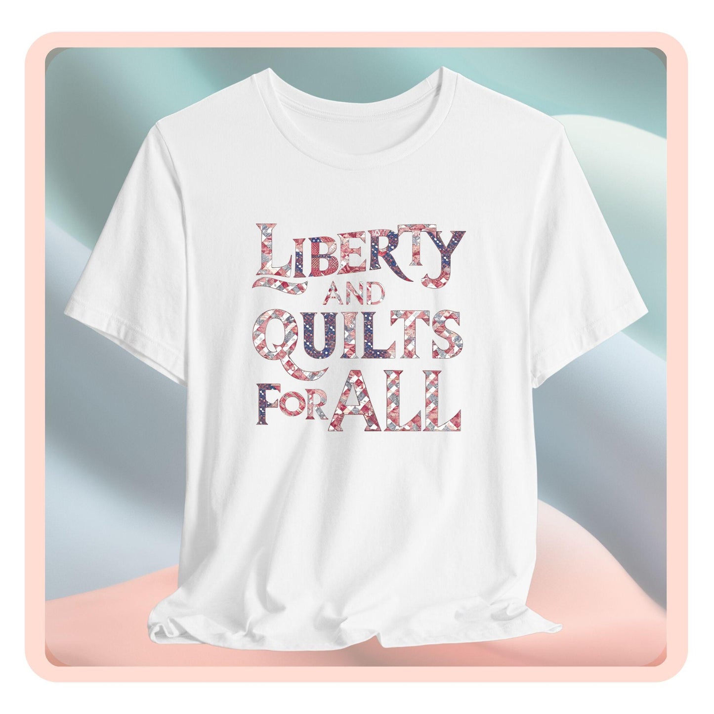 A T-shirt featuring text "LIBERTY AND QUILTS FOR ALL" in large decorative letters filled with various quilt patterns in red, white, and blue.