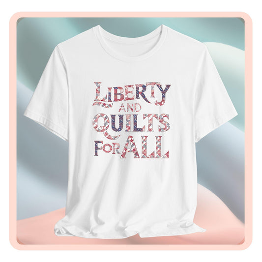 A T-shirt featuring text "LIBERTY AND QUILTS FOR ALL" in large decorative letters filled with various quilt patterns in red, white, and blue.