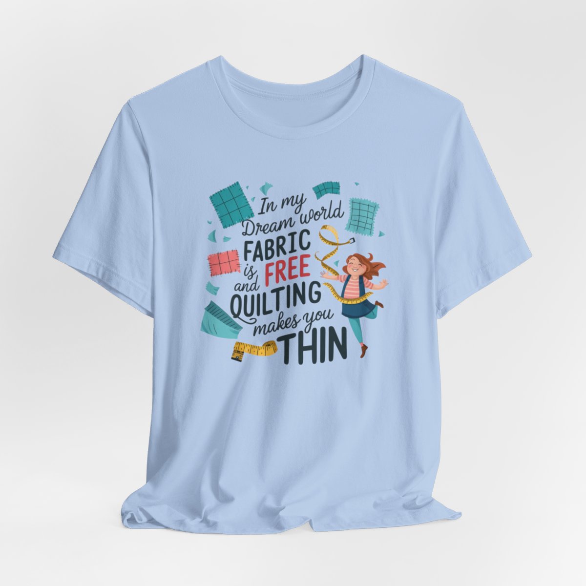 A Baby Blue funny quilting T-Shirt with the phrase Fabric is Free and Quilting Makes You Thin in a fun font with a cheerful quilter jumping for joy