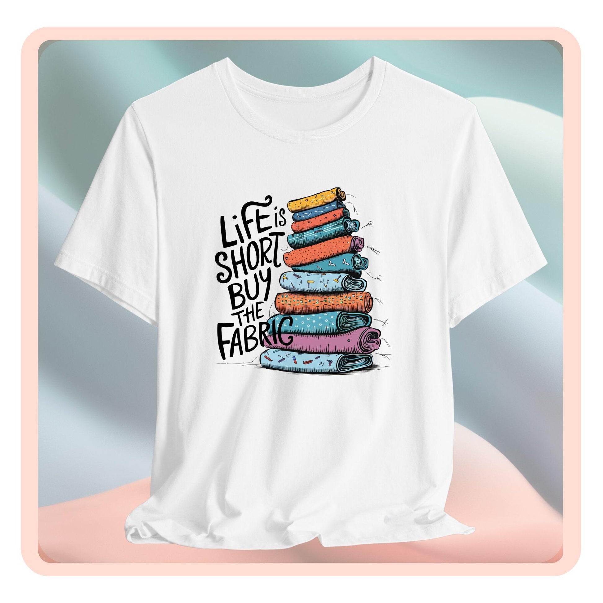 A fun T-Shirt with the phrase Life is Short, Buy the Fabric with the label 'Life is Short, Buy the Fabric' next to a graphic of a fun pile of fabric