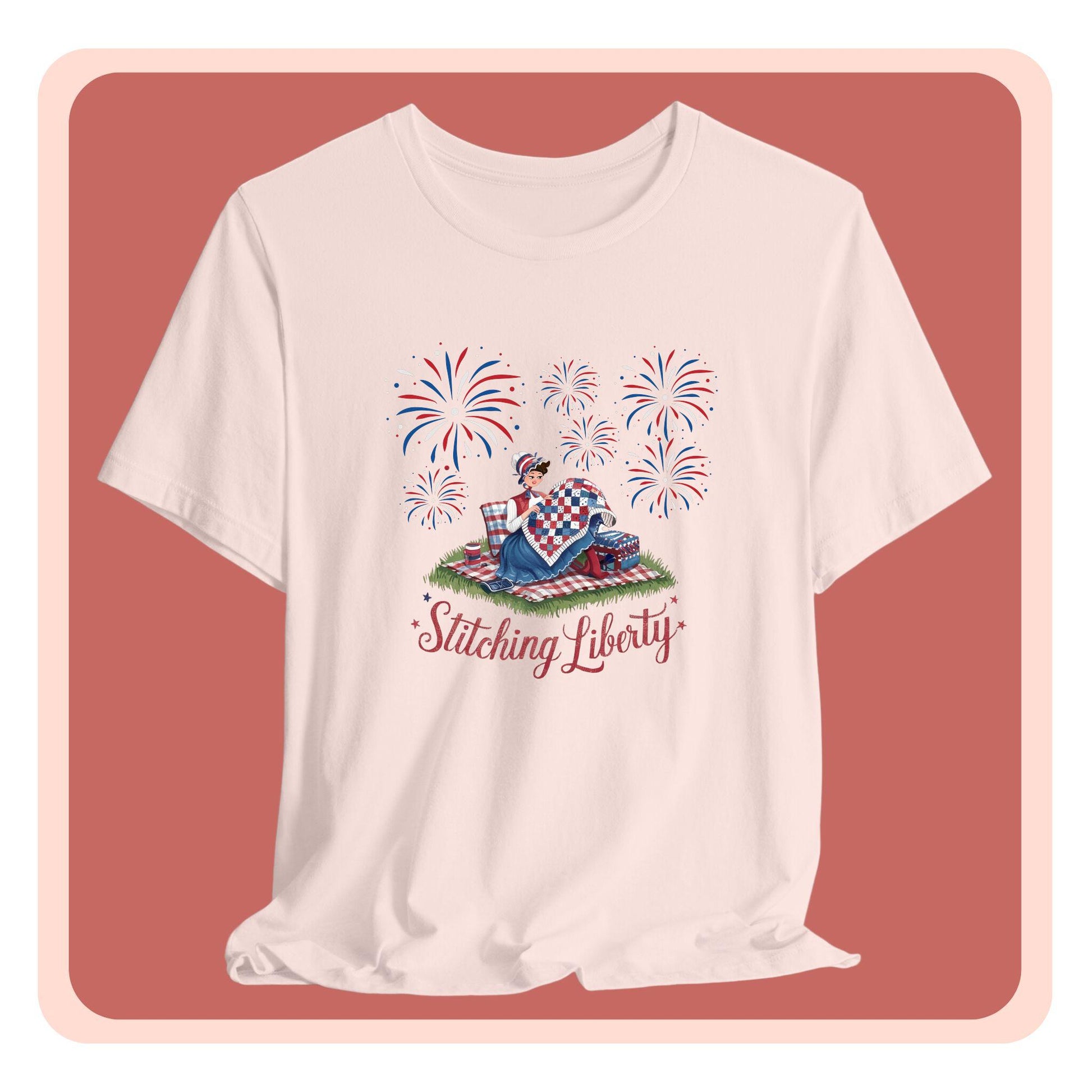 A T-shirt with illustrated scene of a colonial woman quilting a patriotic blanket, surrounded by fireworks. Text reads "Stitching Liberty" in a decorative font.