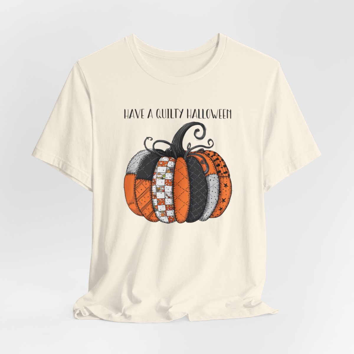 A Natural Halloween Quilting T-Shirt featuring patchwork pumpkin with various quilt patterns. Mix of Halloween and traditional quilt motifs. Intricate stitching details. Text reads "Have a Quilty Halloween". Ideal for quilters who love Halloween.