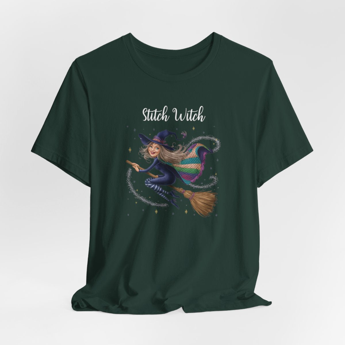 A Forest Halloween Quilting T-Shirt featuring a witch riding broomstick on t-shirt design. Colorful patchwork quilt cape with various patterns. Sparkling magic and stars. Text reads "Stitch Witch". Ideal for quilters who enjoy magical themes.