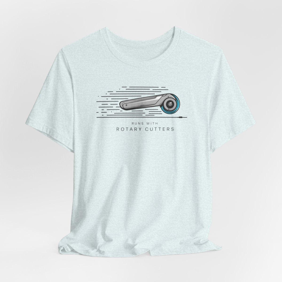 A Heather Ice Blue T-shirt featuring minimalist graphic of a sleek rotary cutter in motion with speed lines. Text below reads "RUNS WITH ROTARY CUTTERS" in a modern font.