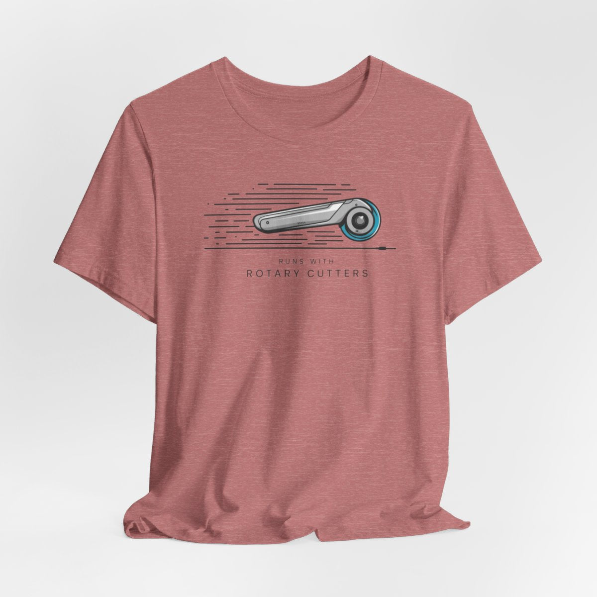 A Heather Mauve T-shirt featuring minimalist graphic of a sleek rotary cutter in motion with speed lines. Text below reads "RUNS WITH ROTARY CUTTERS" in a modern font.