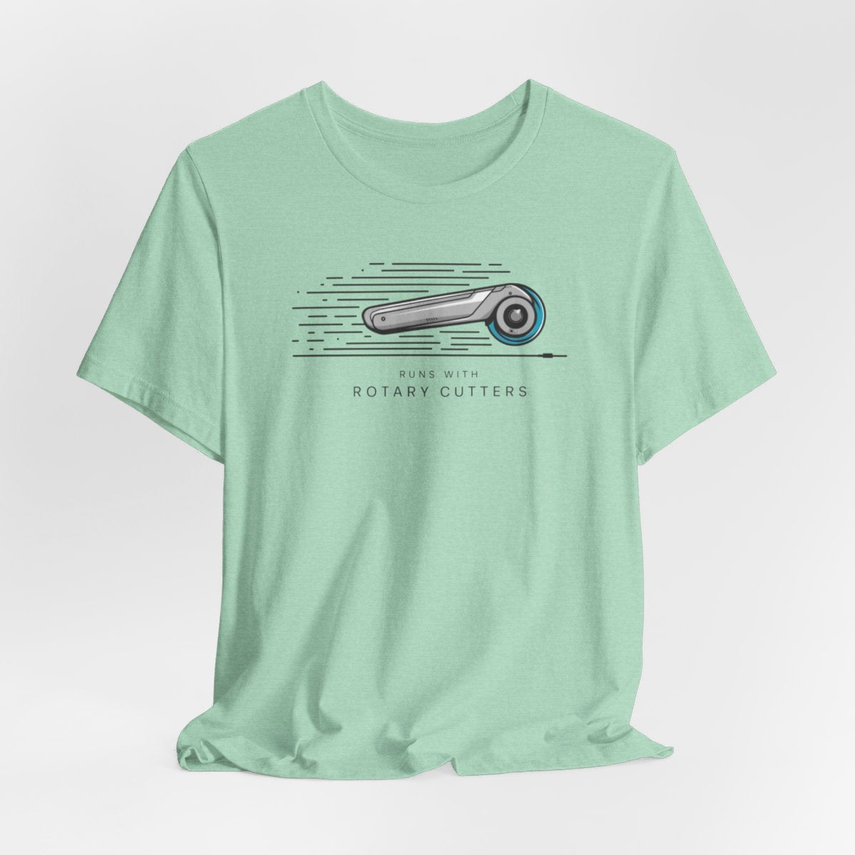 A Heather Mint T-shirt featuring minimalist graphic of a sleek rotary cutter in motion with speed lines. Text below reads "RUNS WITH ROTARY CUTTERS" in a modern font.