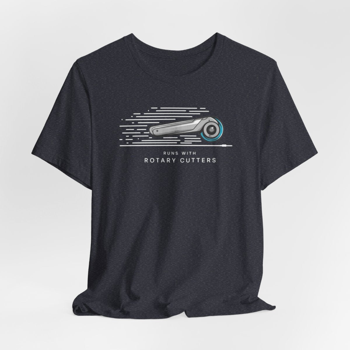 A Heather Navy T-shirt featuring minimalist graphic of a sleek rotary cutter in motion with speed lines. Text below reads "RUNS WITH ROTARY CUTTERS" in a modern font.